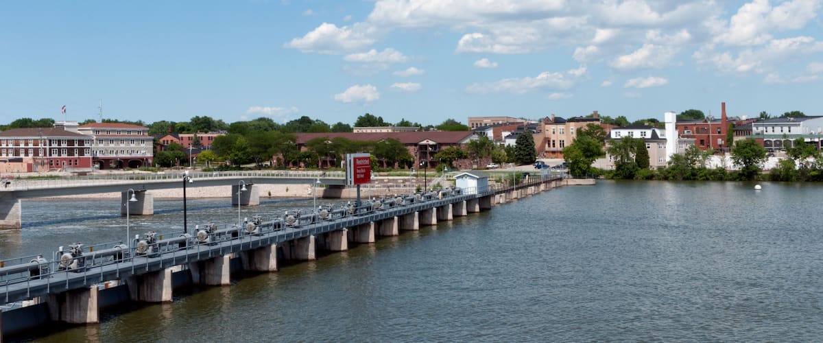 A bridge over a river with buildings and trees in the background.