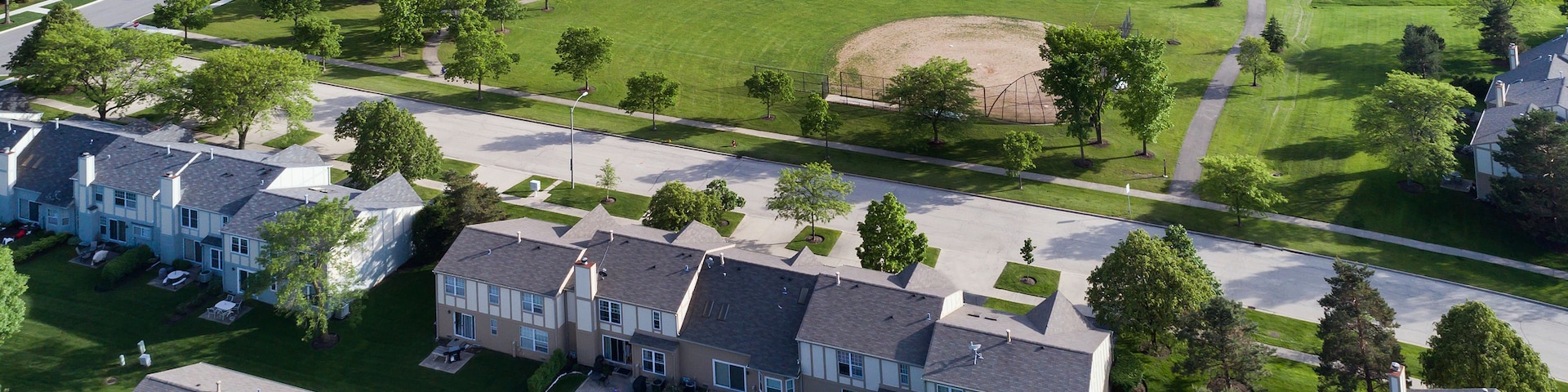 Zona residencial con casas, un parque con un campo de béisbol y una cancha de tenis.