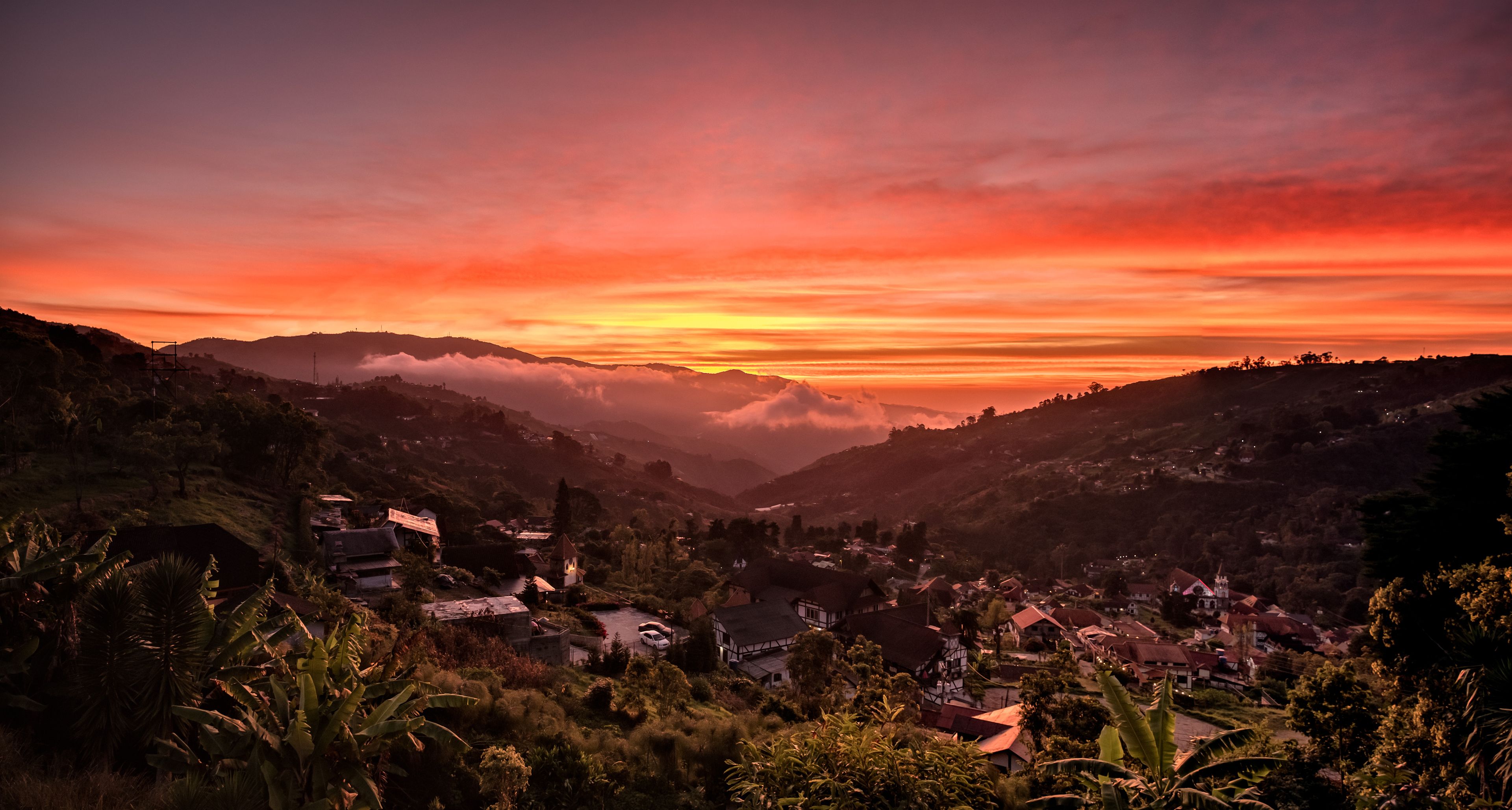 A village nestled in a valley with a sunset sky.