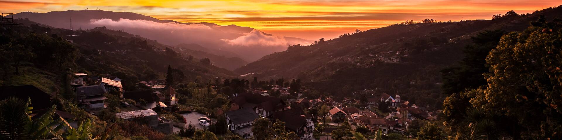 A valley with a sunset, houses, and mountains.