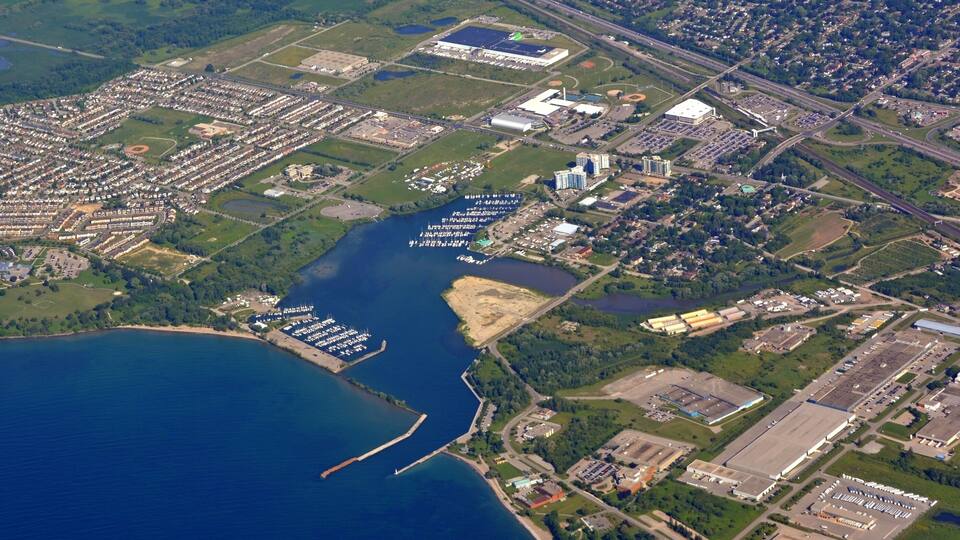 An aerial view of a coastal city with a marina, industrial areas, and residential zones.
