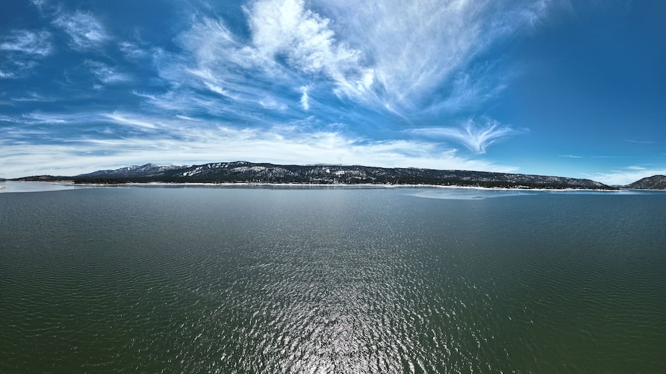 A large body of water with a clear sky and distant mountains.