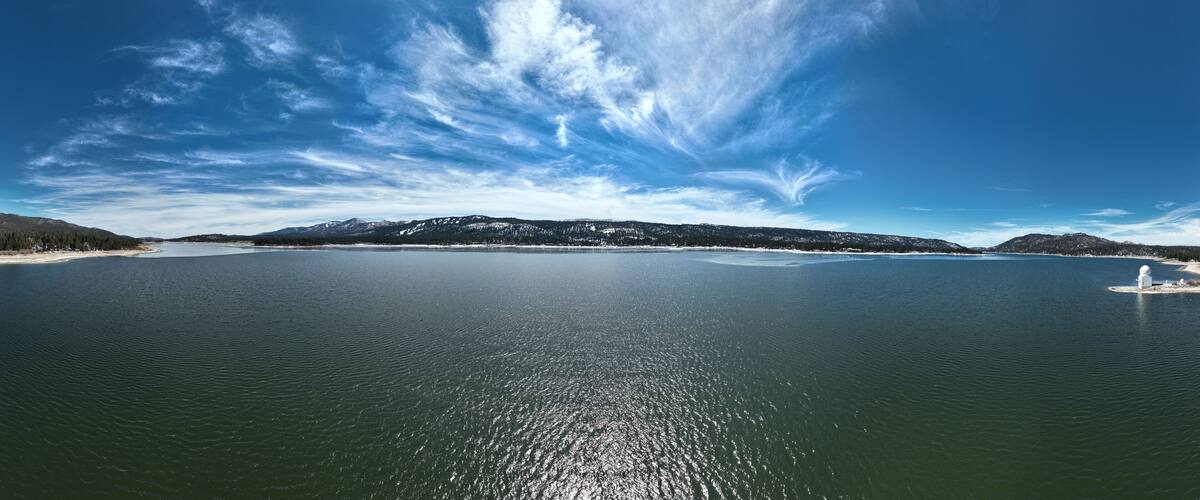 A large body of water with a clear sky and distant mountains.