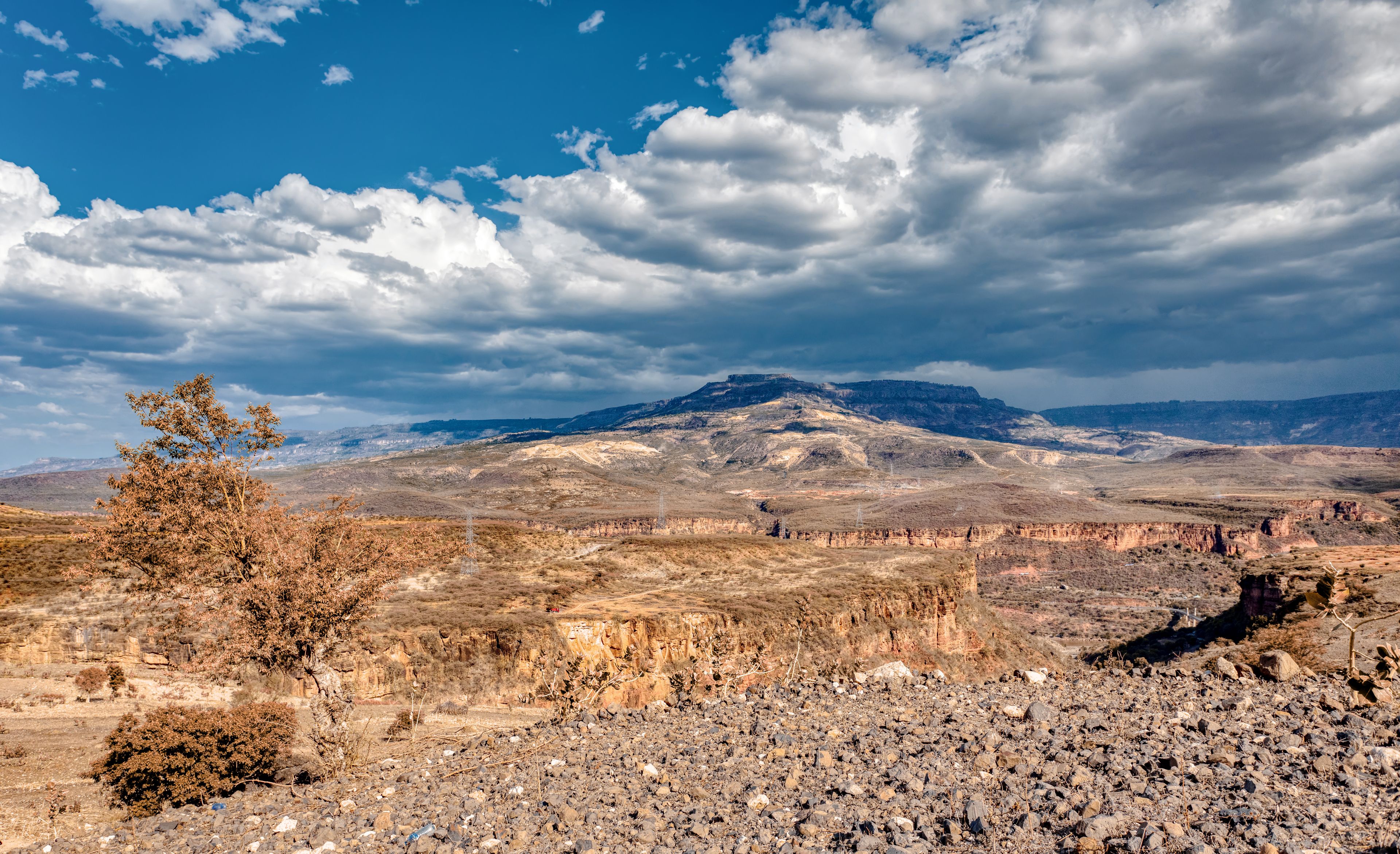 A rugged mountain landscape with sparse vegetation and a clear sky.