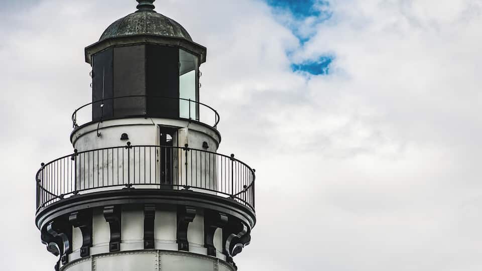 A lighthouse with a domed top and a balcony.