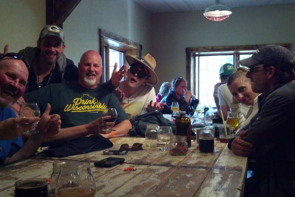 Un groupe de personnes est assis autour d’une table en bois dans une pièce dotée d’une fenêtre et d’un luminaire suspendu.