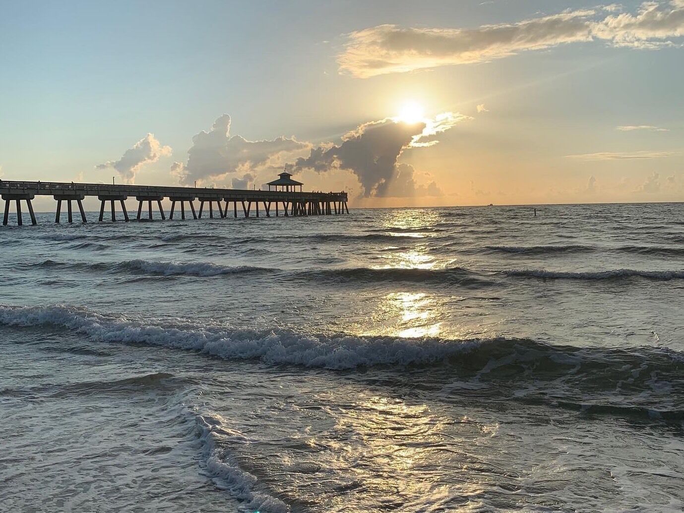 A pier extending into the ocean with waves crashing against it.