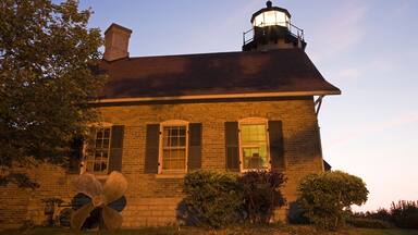 A brick building with a lighthouse on the roof, surrounded by trees and bushes.