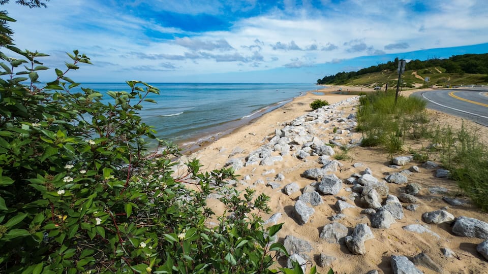 A beach with rocky shoreline, clear blue sky, and calm sea.