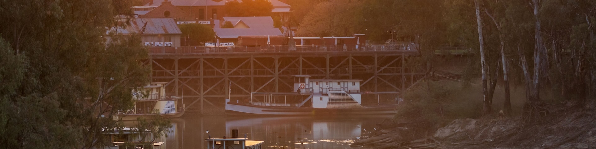 Un río con un barco amarrado cerca de un puente, rodeado de árboles y edificios.