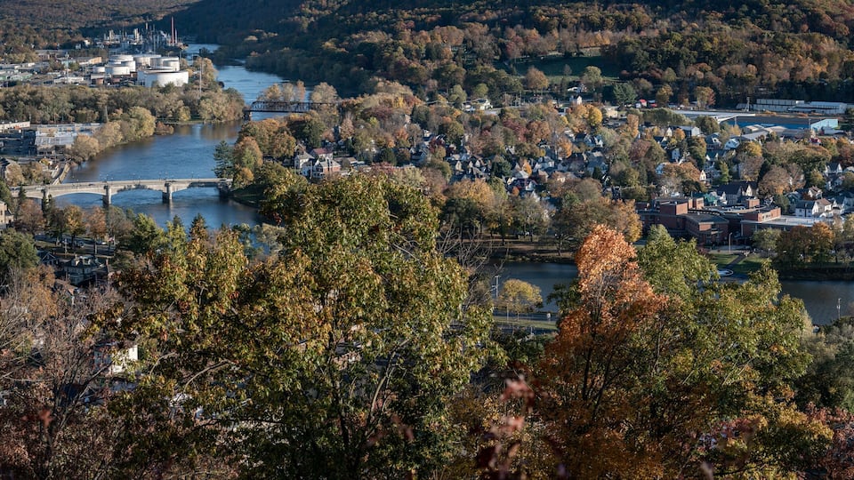 A river flowing through a town surrounded by autumn foliage.
