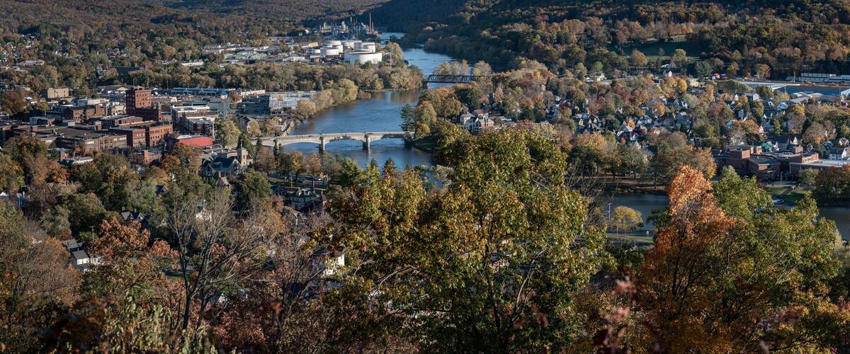 A river flowing through a town surrounded by autumn foliage.