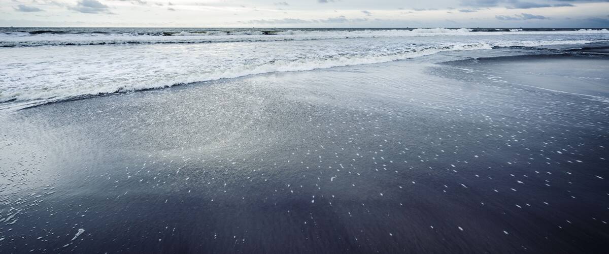 A beach with waves and a cloudy sky.