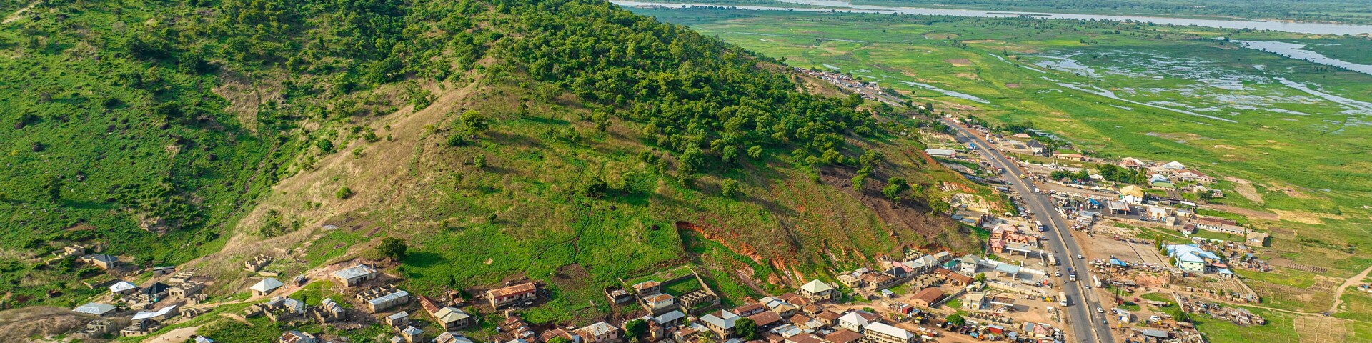 Aerial view of a beautiful village nestled among hills and mountains with greenery and homes, Lokoja, Nigeria.