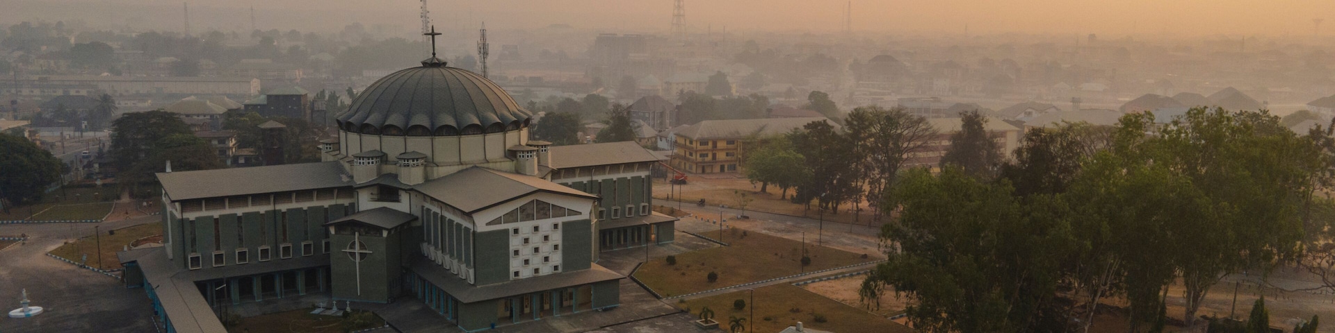 Aerial view of the beautiful cityscape featuring impressive buildings and a dome under a hazy sunset, Owerri Municipal, Nigeria.