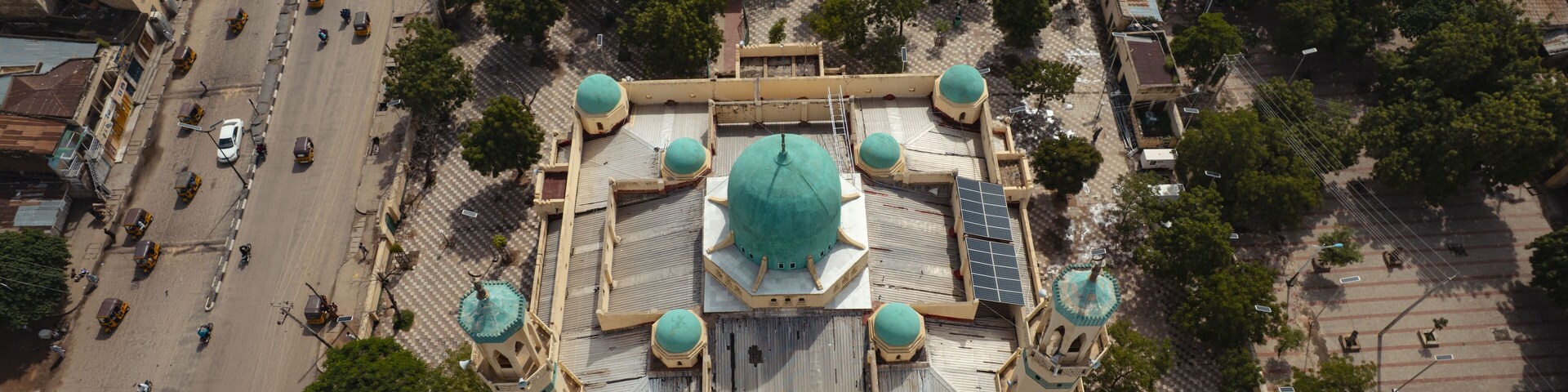 Aerial view of a grand mosque with a turquoise dome and minarets, juxtaposed against the bustling Emir Palace Road, Kano, Kano, Nigeria.