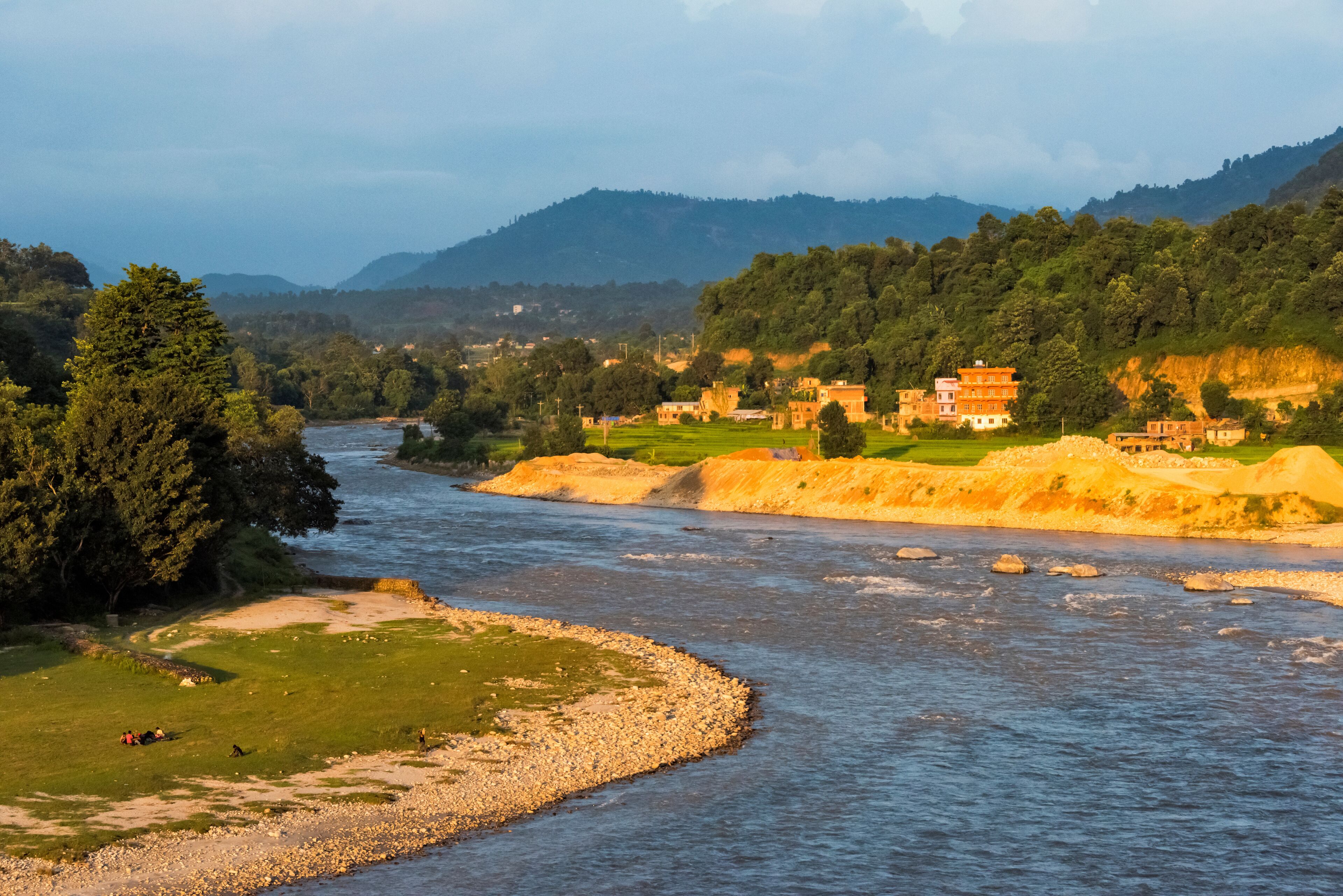 A river flowing through a valley with a temple and lush greenery.
