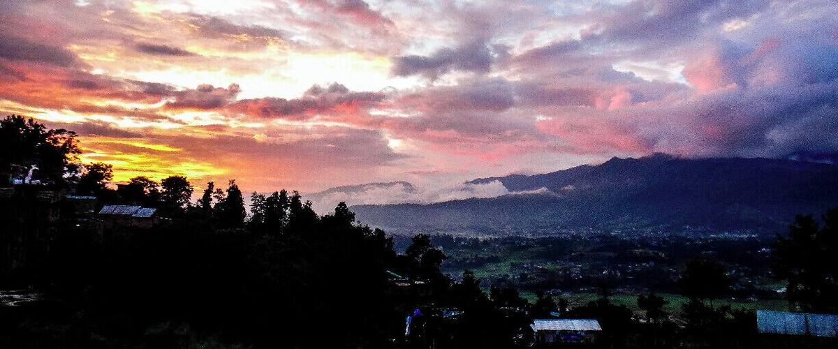A sunset over a mountainous landscape with scattered clouds.