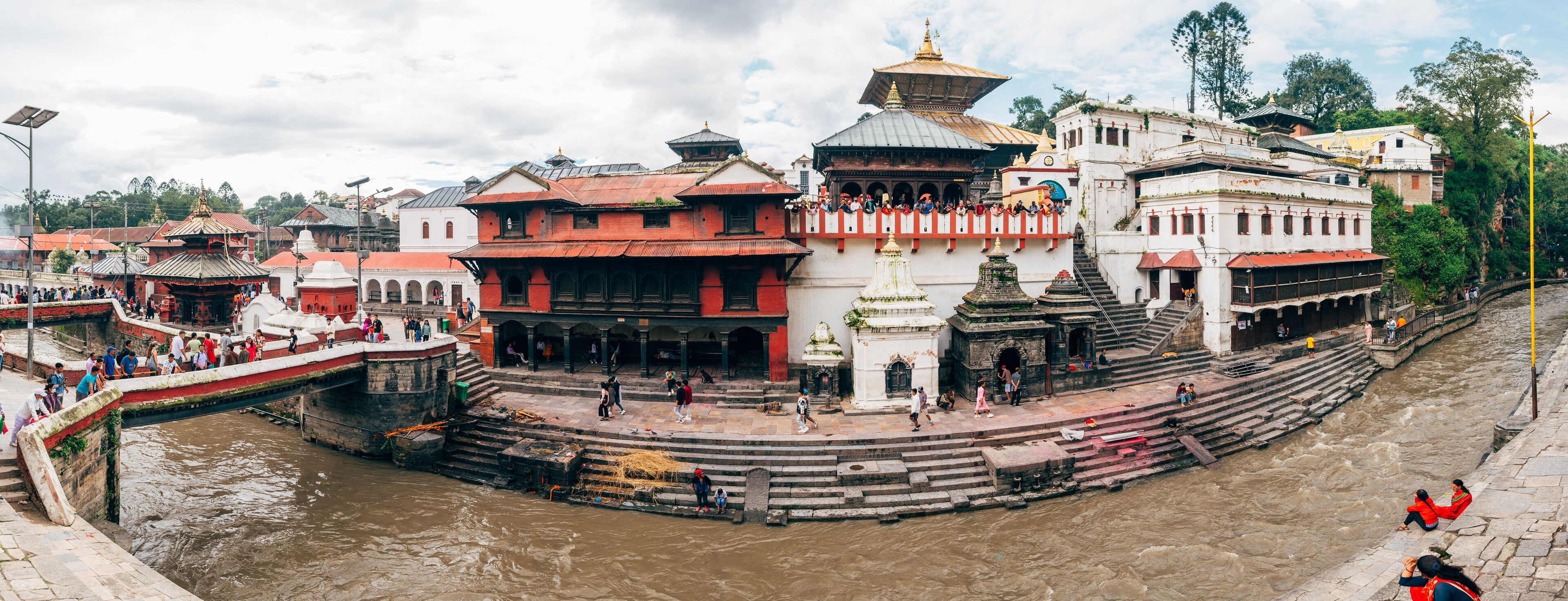 A riverside temple complex with steps leading down to the water, surrounded by traditional buildings.