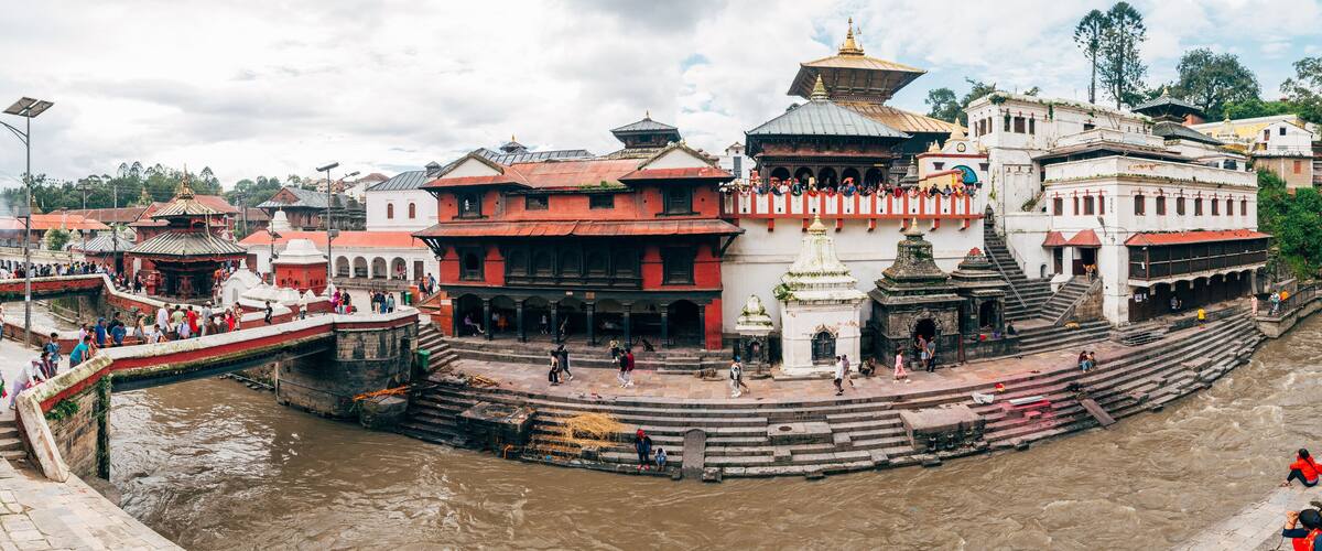 A riverside temple complex with steps leading down to the water, surrounded by traditional buildings.