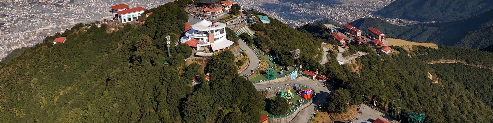 Aerial view of Chandragiri Hills Resort nestled amidst lush greenery, overlooking Kathmandu Valley under a clear sky, Chandragiri, Bagmati Province, Nepal.
