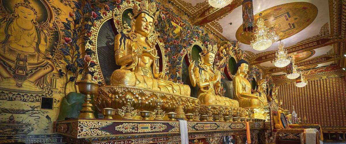 A richly decorated temple interior with golden statues and intricate wall carvings.