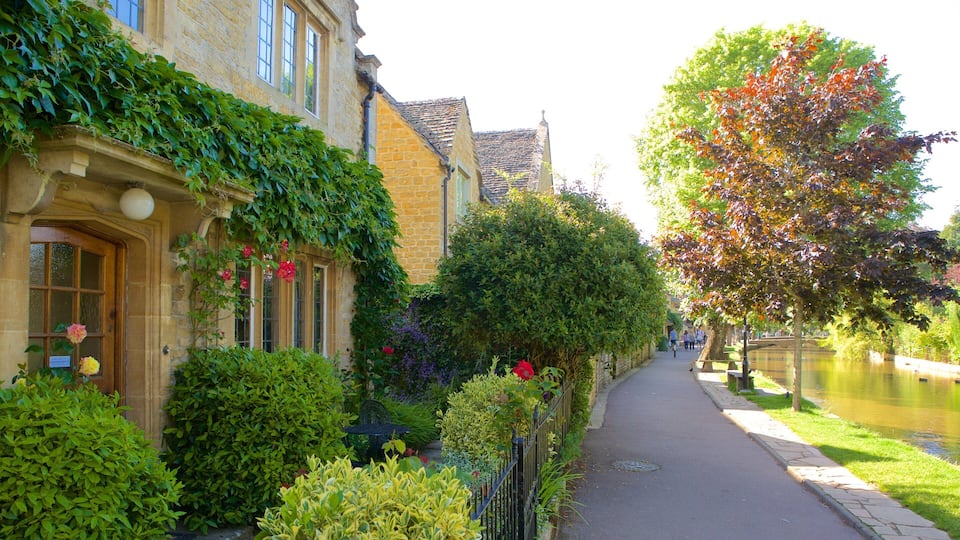 A quaint street lined with stone buildings, lush greenery, and a canal.