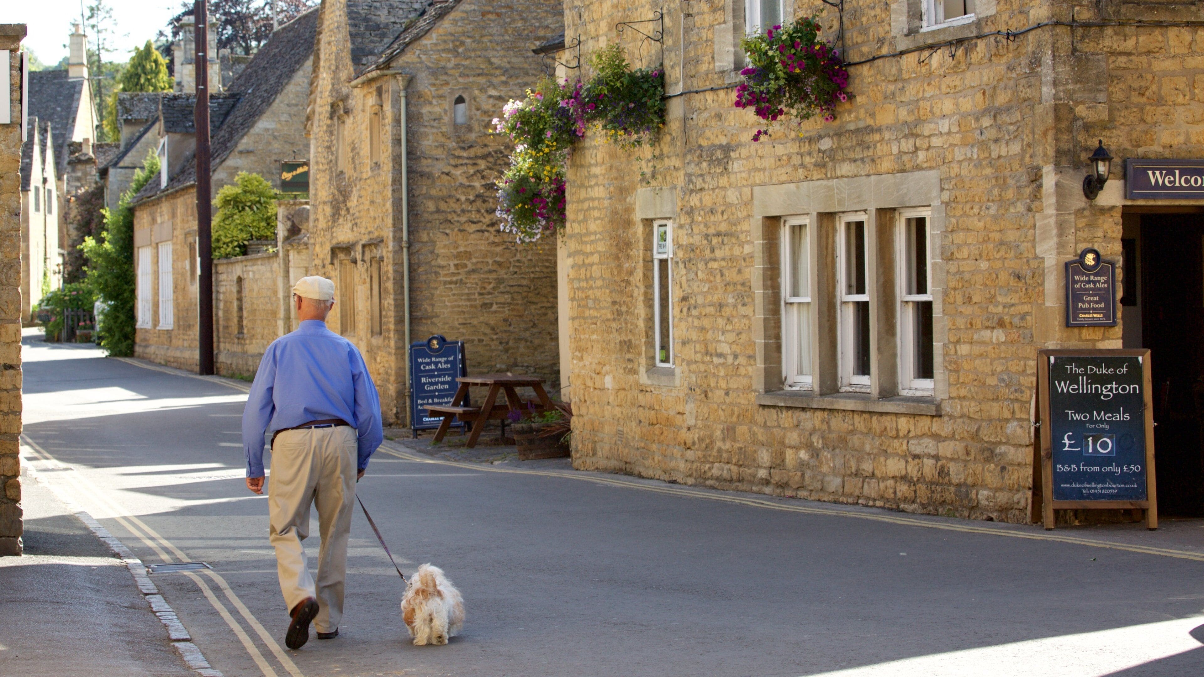 Bourton-on-Water qui includes petite ville ou village et scènes de rue aussi bien que homme