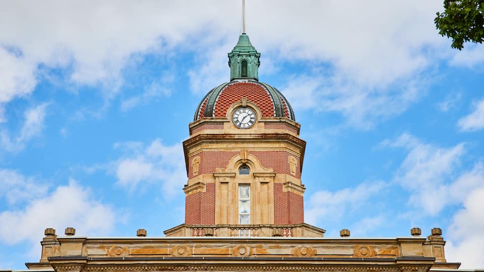 A clock tower with a dome and a spire against a blue sky.
