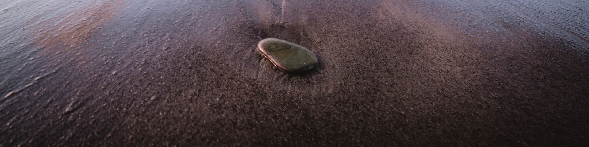 A beach with waves and a surfboard on the sand.