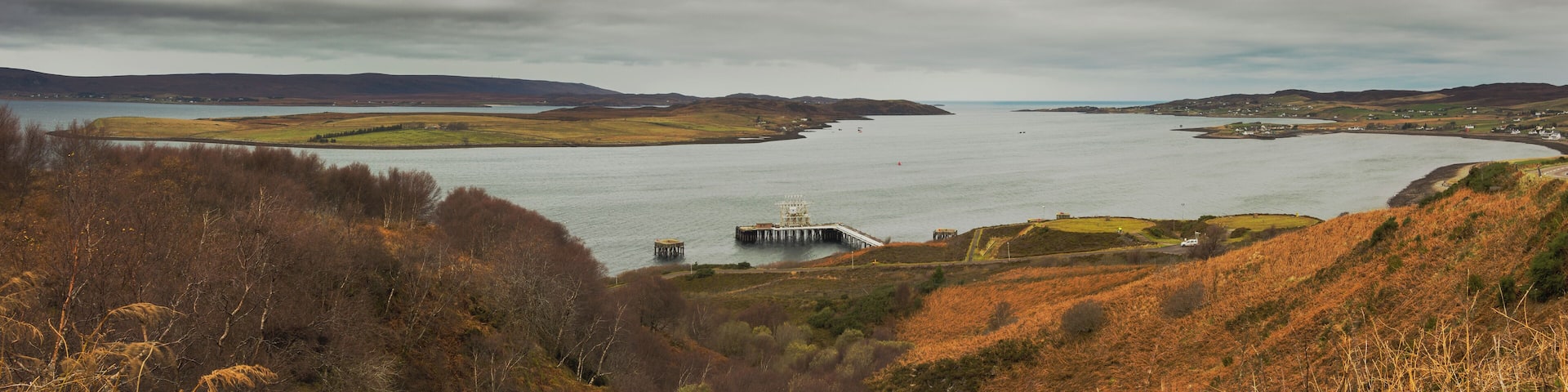 Panorama overlooking Loch Ewe. The NATO Petroleum, Oil and Lubricants (POL) depot can be seen in the foreground; the villages of Aultbea, Ormiscaig and Mellon Charles are visible along the Western shore of the loch (right hand side); North of the POL depot is the Isle of Ewe and in the background on the left hand side behind the island, part of the Eastern shore are visible, including the beach at Firemore.