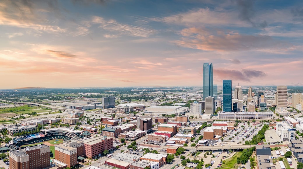 A cityscape with a prominent skyscraper, a stadium, and surrounding urban buildings.