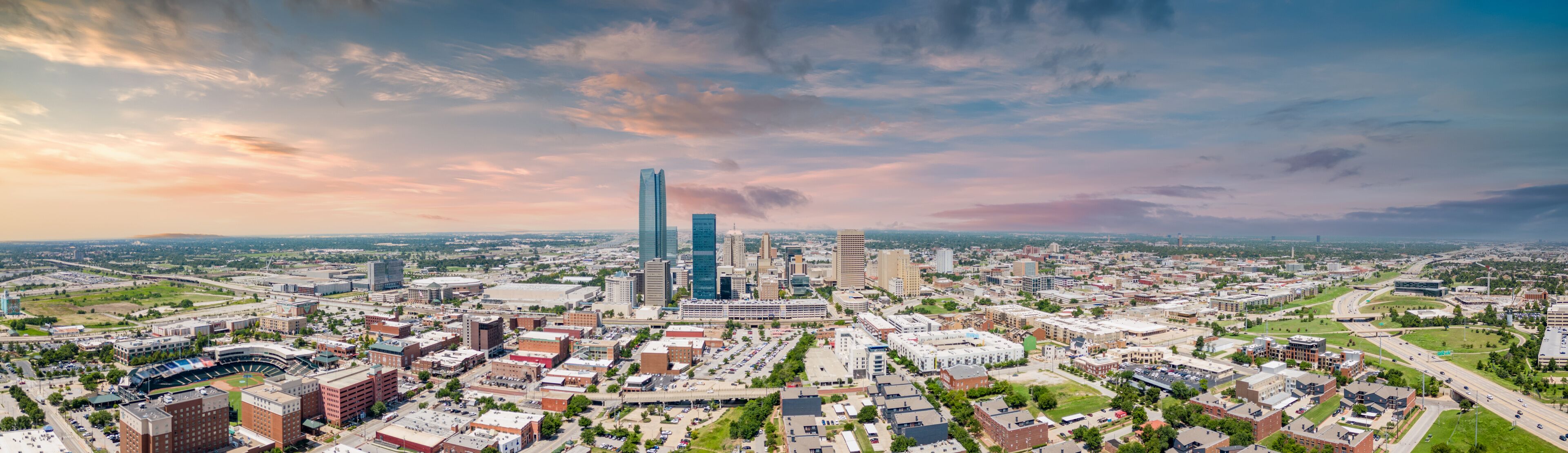 A cityscape with a prominent skyscraper, a stadium, and surrounding urban buildings.