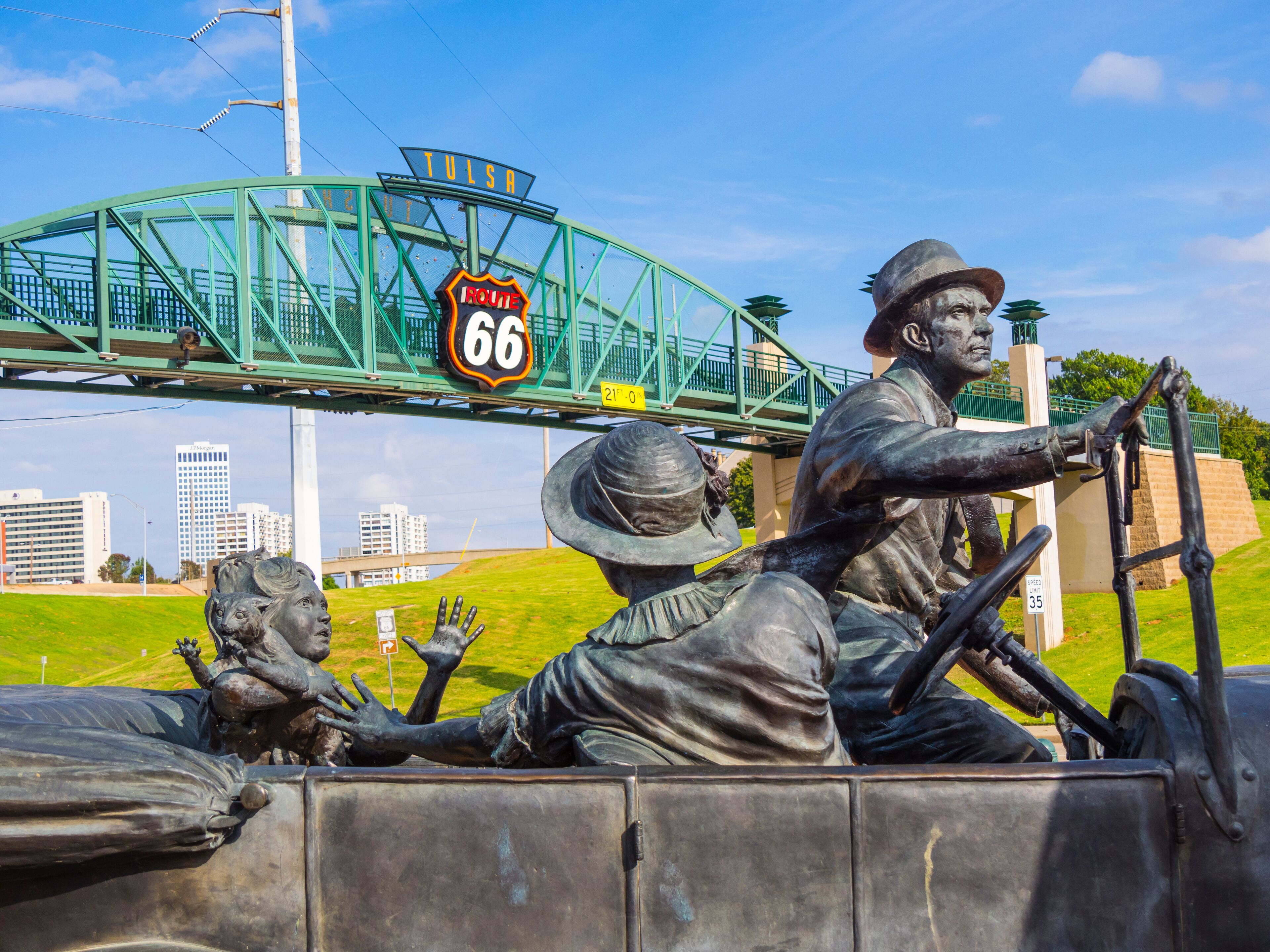 A statue of a man driving a truck, a green bridge, and the number 66 on Route 66.