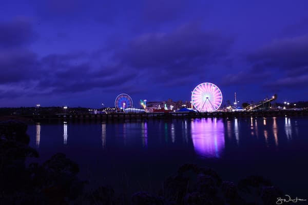 Ein Riesenrad und ein Gewässer bei Nacht.