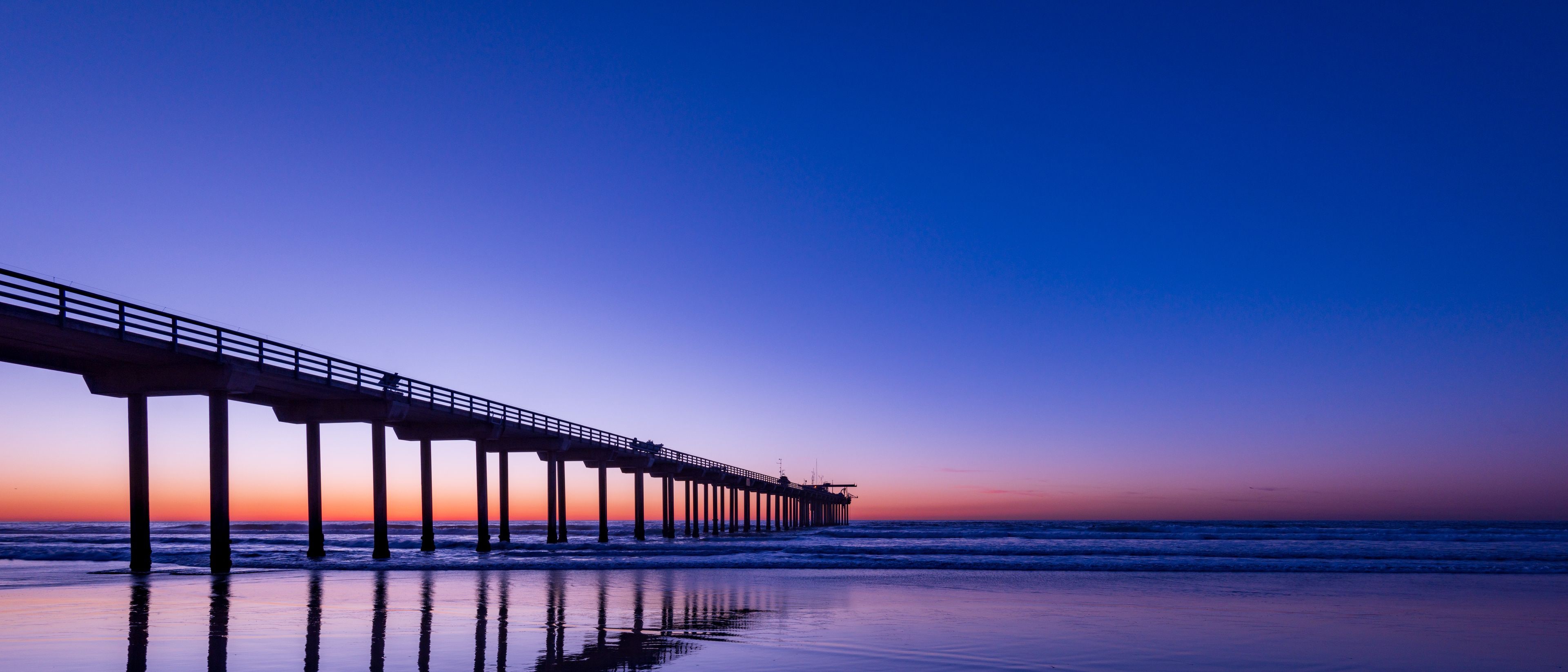 A pier extending into the ocean at sunset.
