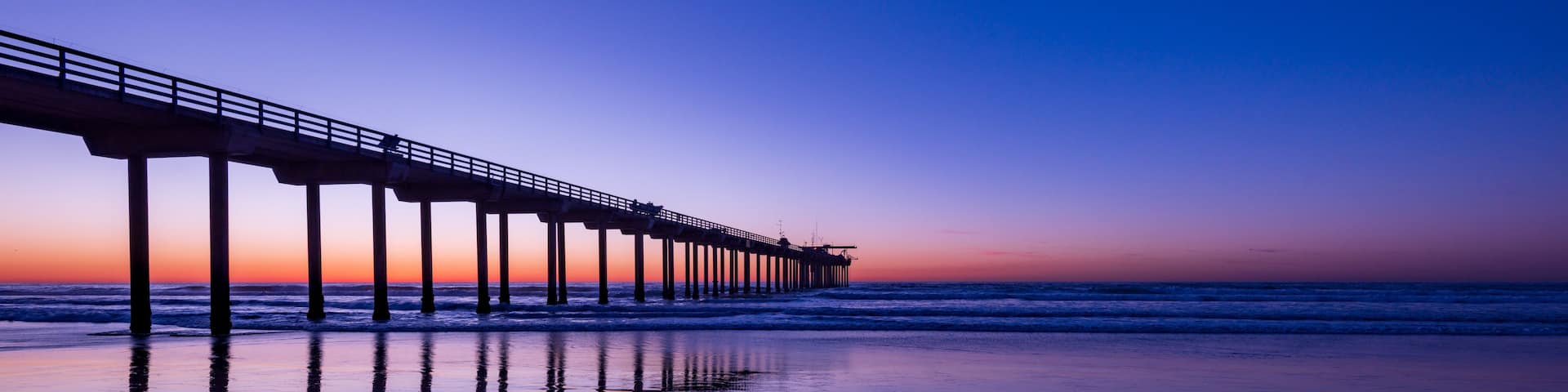 A pier extending into the ocean at sunset.