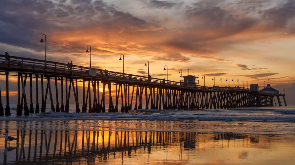 A pier extending into the water with a sunset in the background.