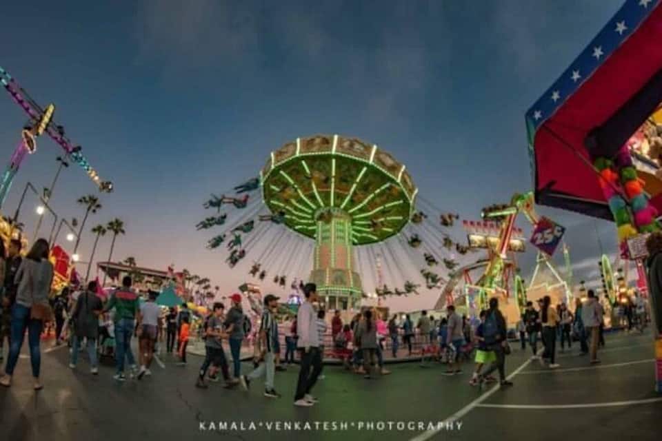 A Ferris wheel, carnival rides, and a crowd at an amusement park.