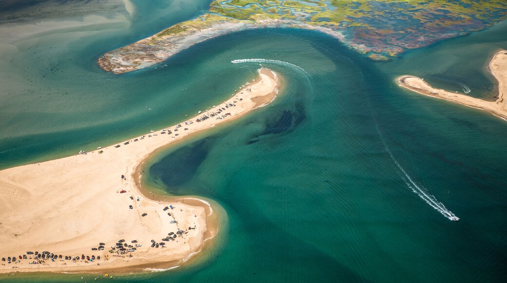 Vista aérea de una zona costera con aguas azul turquesa, playas de arena y un rastro de botes.