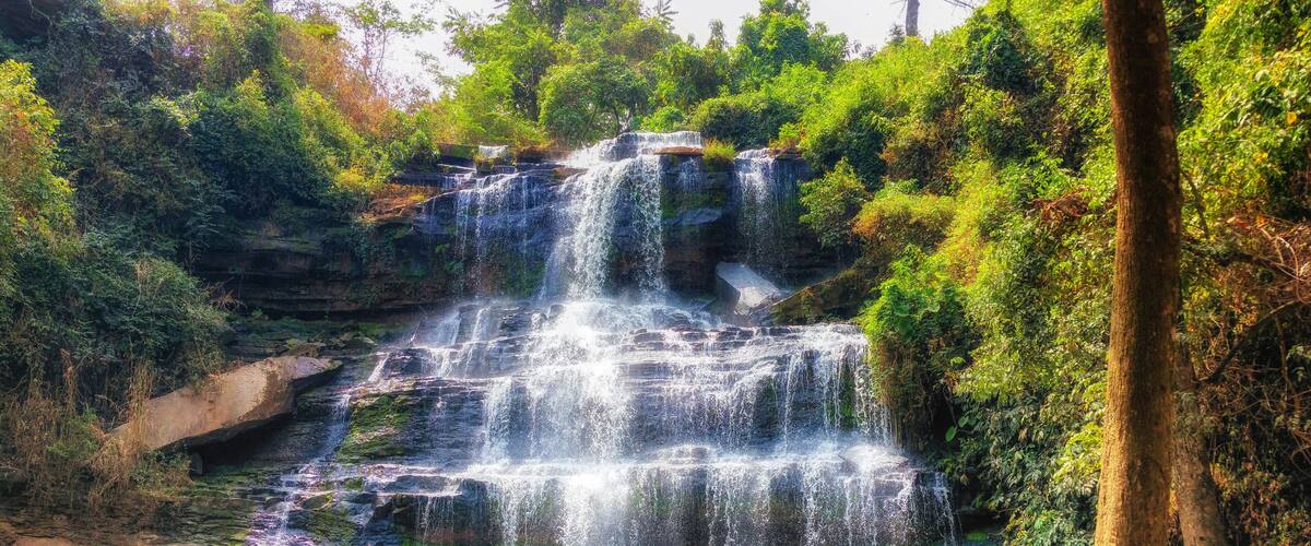 A multi-tiered waterfall surrounded by lush greenery.