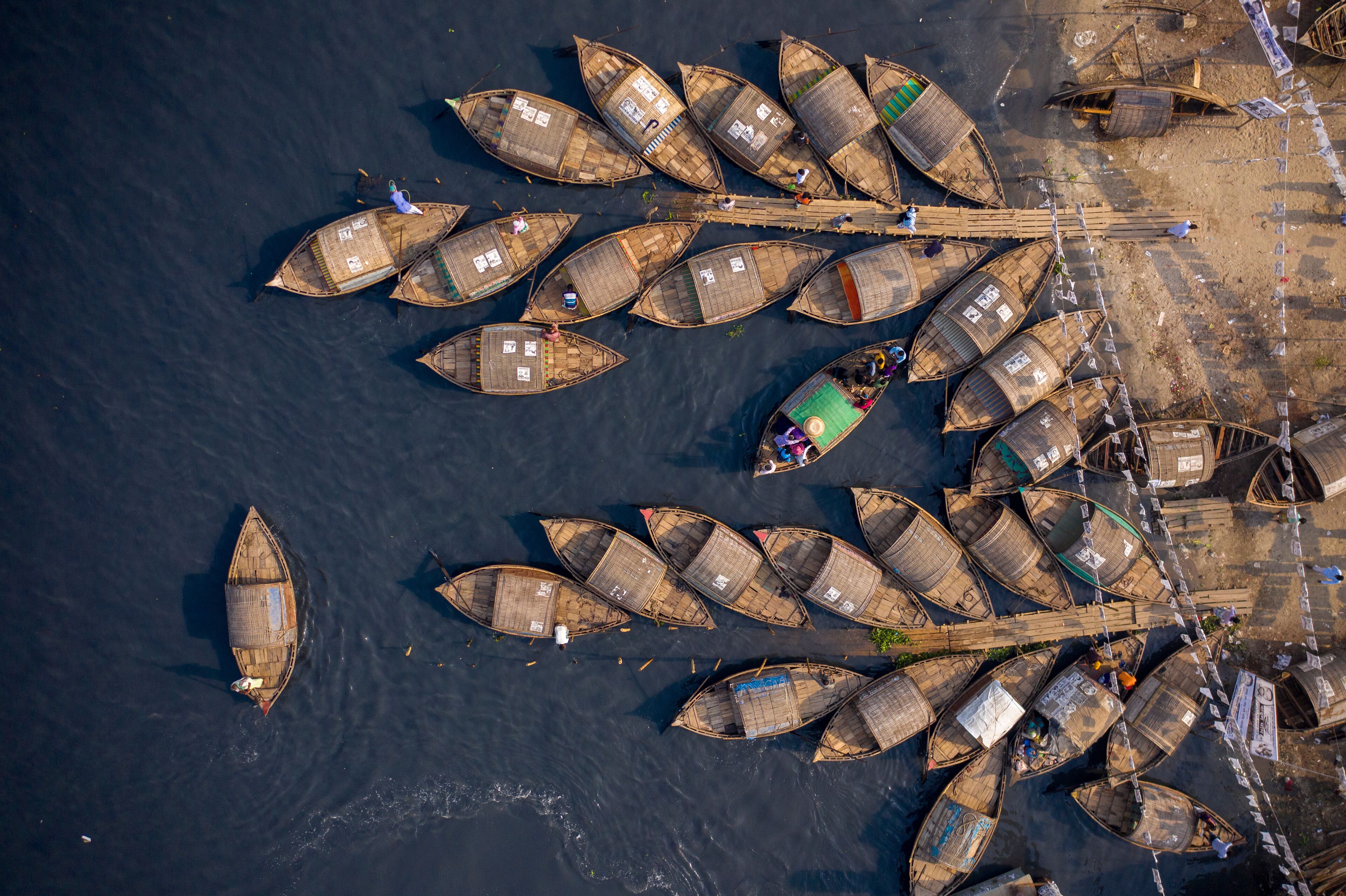 An aerial view of a river with numerous traditional boats docked along the shore.