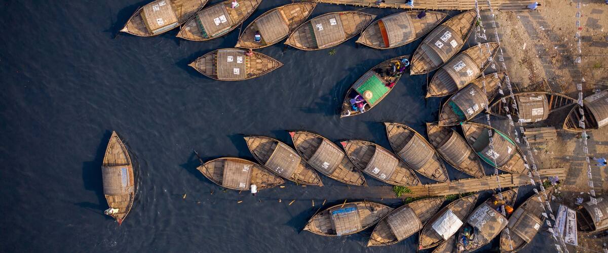 An aerial view of a river with numerous traditional boats docked along the shore.