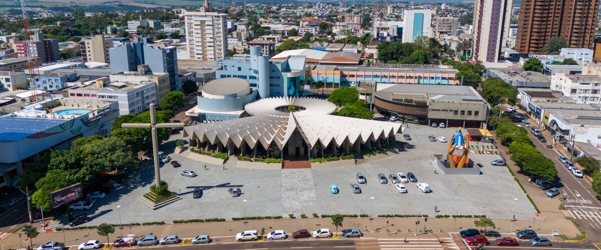 A cityscape with a distinctive circular building surrounded by a parking lot and various other buildings.