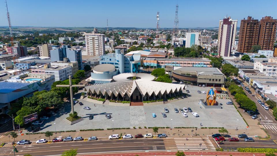 A cityscape with a distinctive circular building surrounded by a parking lot and various other buildings.