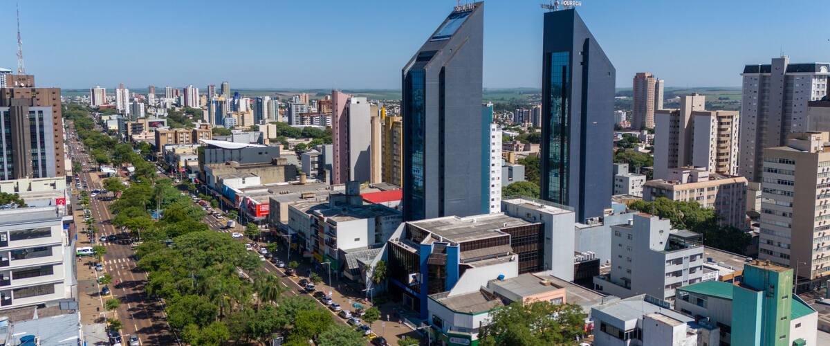 A cityscape with modern skyscrapers, a busy street lined with trees, and a clear blue sky.