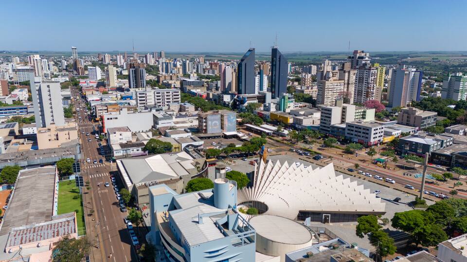 A cityscape with modern buildings, a large stadium, and a river in the background.