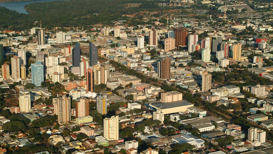 A densely built urban area with numerous high-rise buildings and a river in the background.
