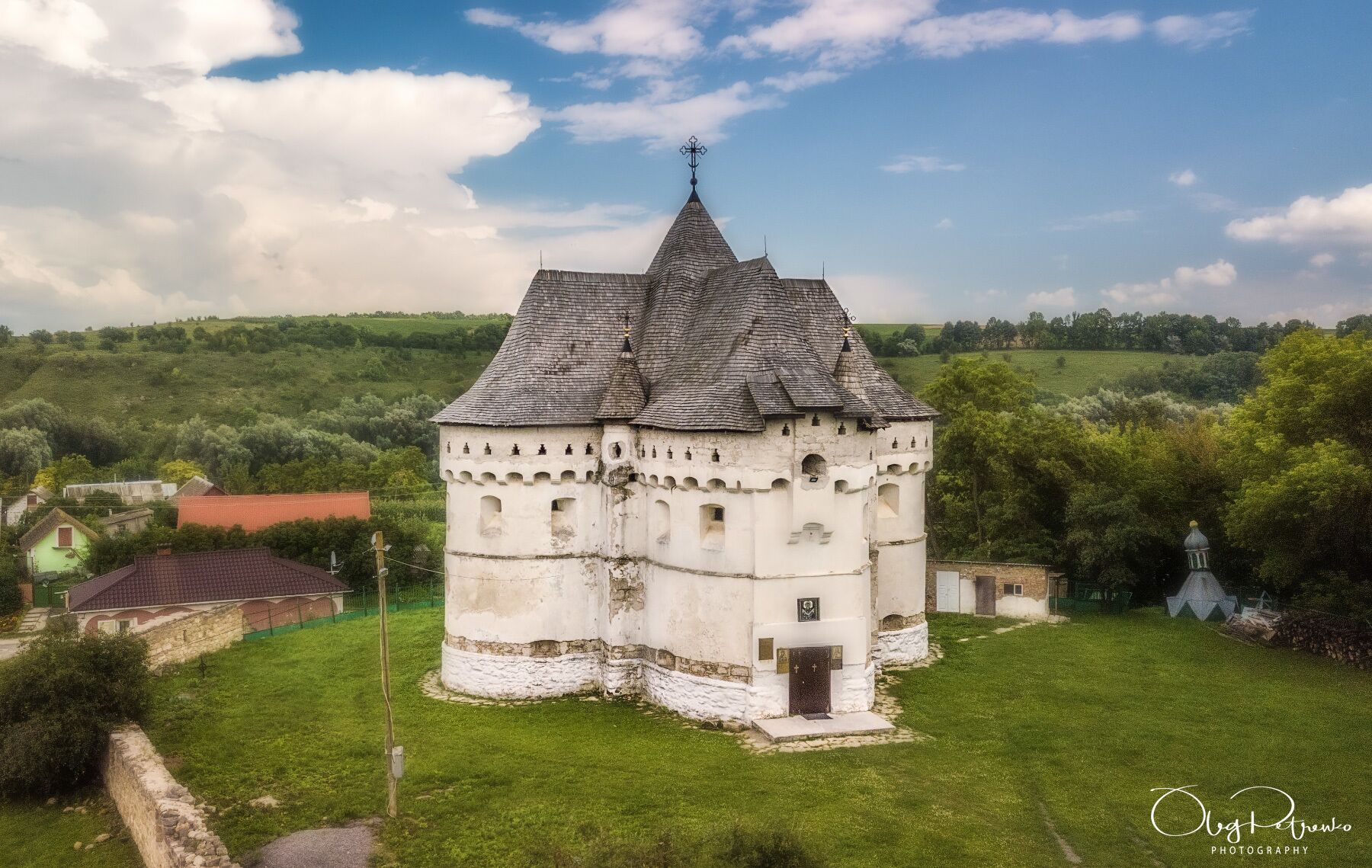 Una torre blanca histórica con techo cónico, rodeada de exuberante vegetación y cielo despejado.