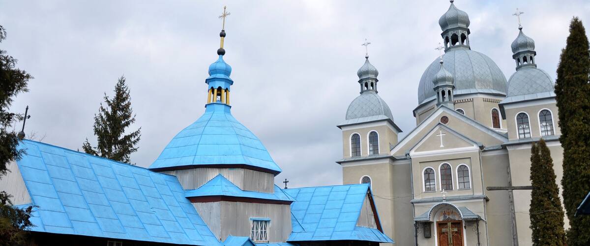 A church with blue domes and a wooden building with a red door.